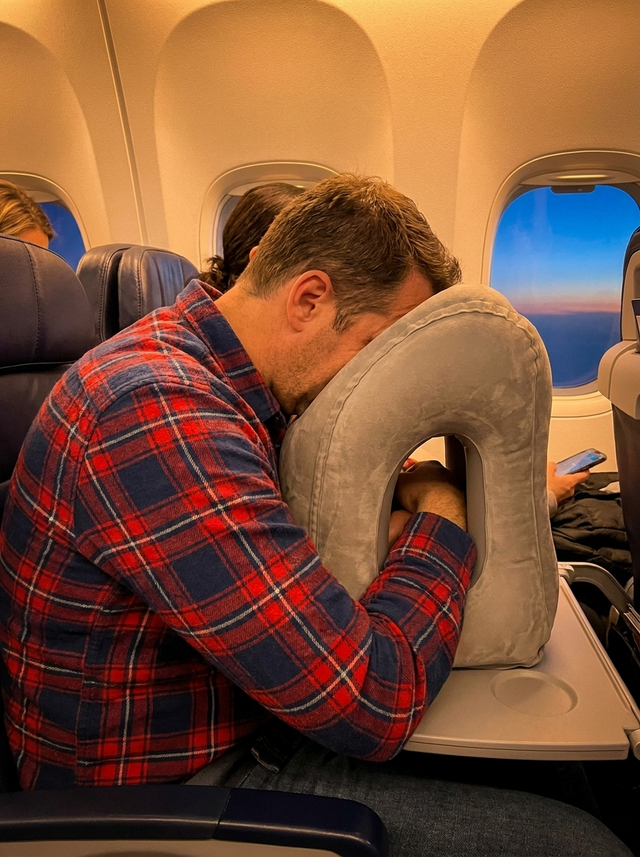 Mark Delaney using the travel pillow on a flight